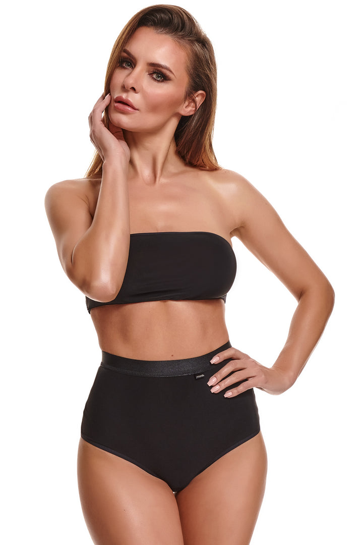 Elegantes zweiteiliges Clubwear-Set Alessia von Demoniq in Schwarz, bestehend aus einem trägerlosen Bandeau-Bustier-Top mit geradem Ausschnitt und einer hochgeschnittenen High-Waist-Panty mit breitem Gummibund, präsentiert von einem brünetten Modell vor weißem Hintergrund.